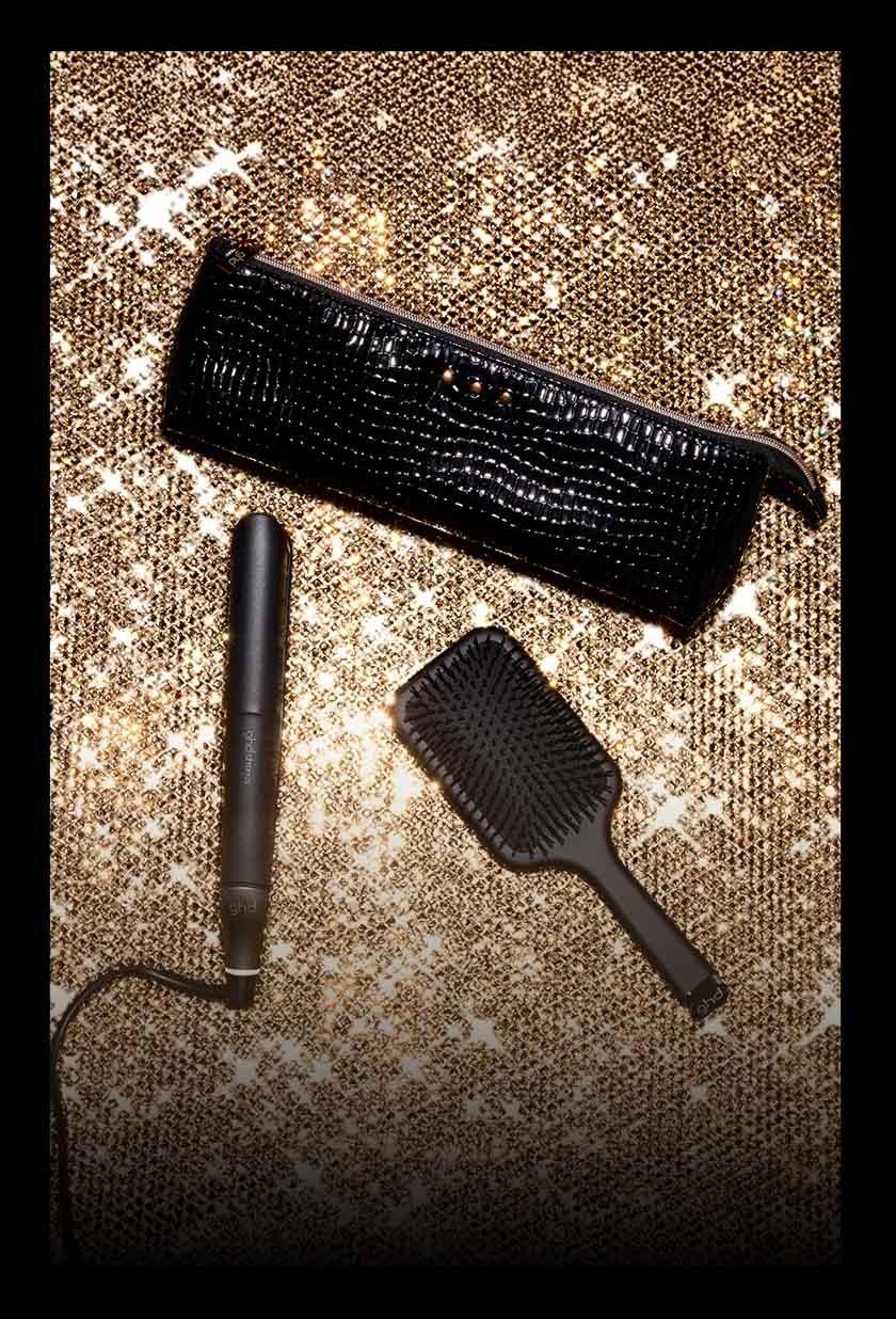 ghd chronos Geschenkset mit Bürste und Hitzeschutztasche vor glitzerndem Hintergrund