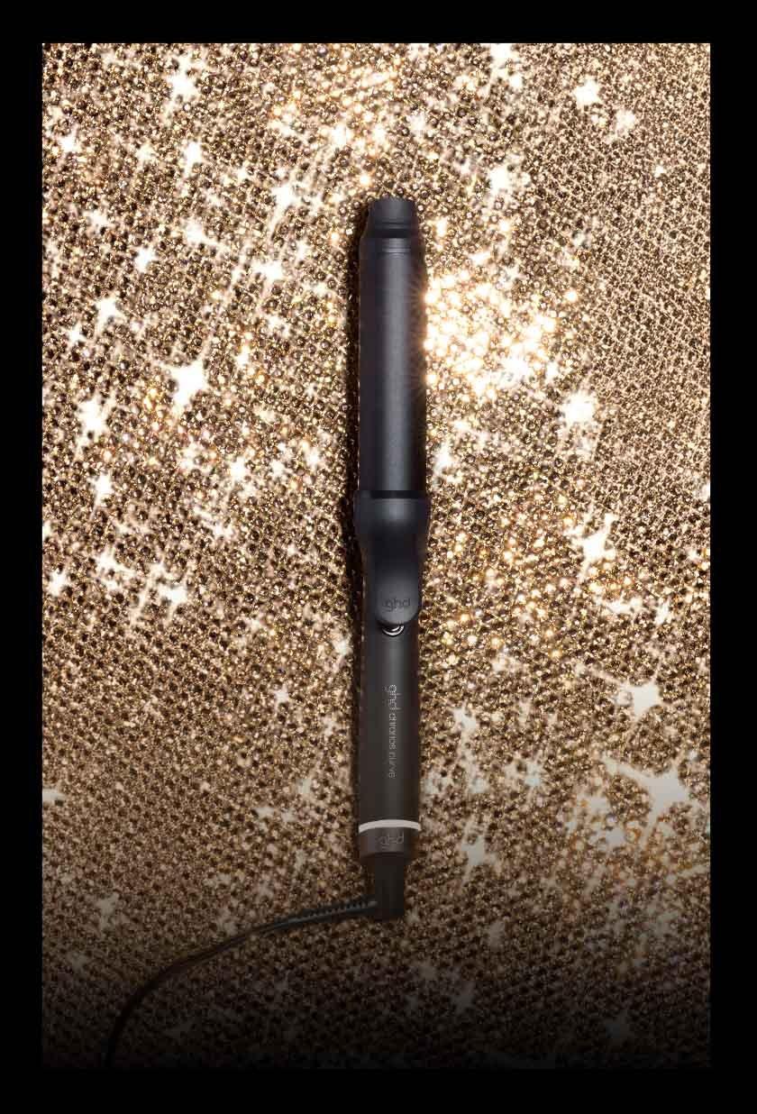 ghd grand tong Lockenstab mit Klammer für glamouröse Locken vor glitzerndem Hintergrund