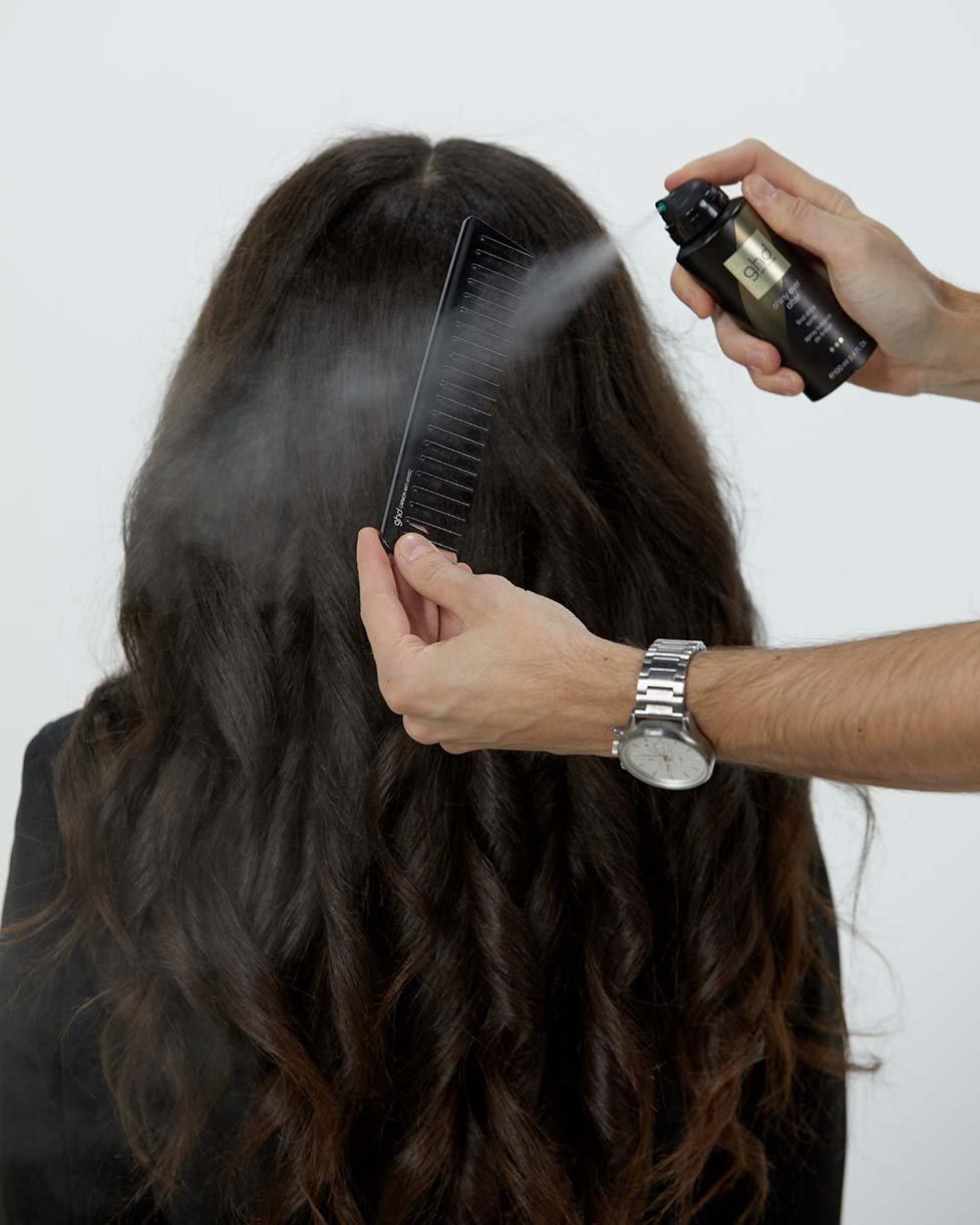 Stylist verteilt ghd Glanzspray auf einem Kamm
