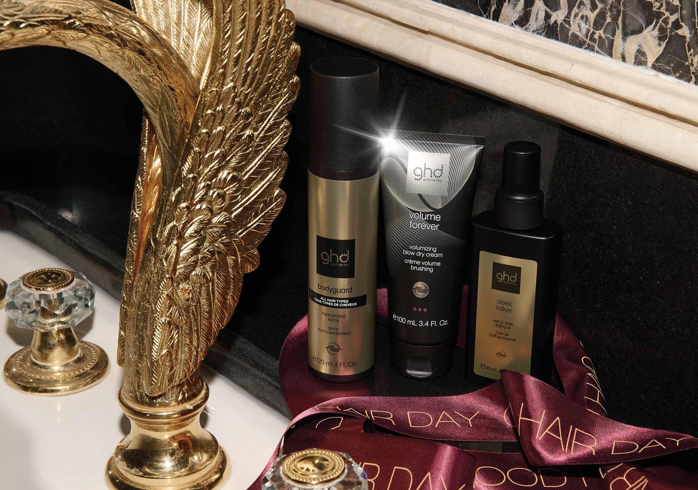 drei verschiedene ghd Stylingprodukte auf einem Waschbecken mit goldenen Armaturen