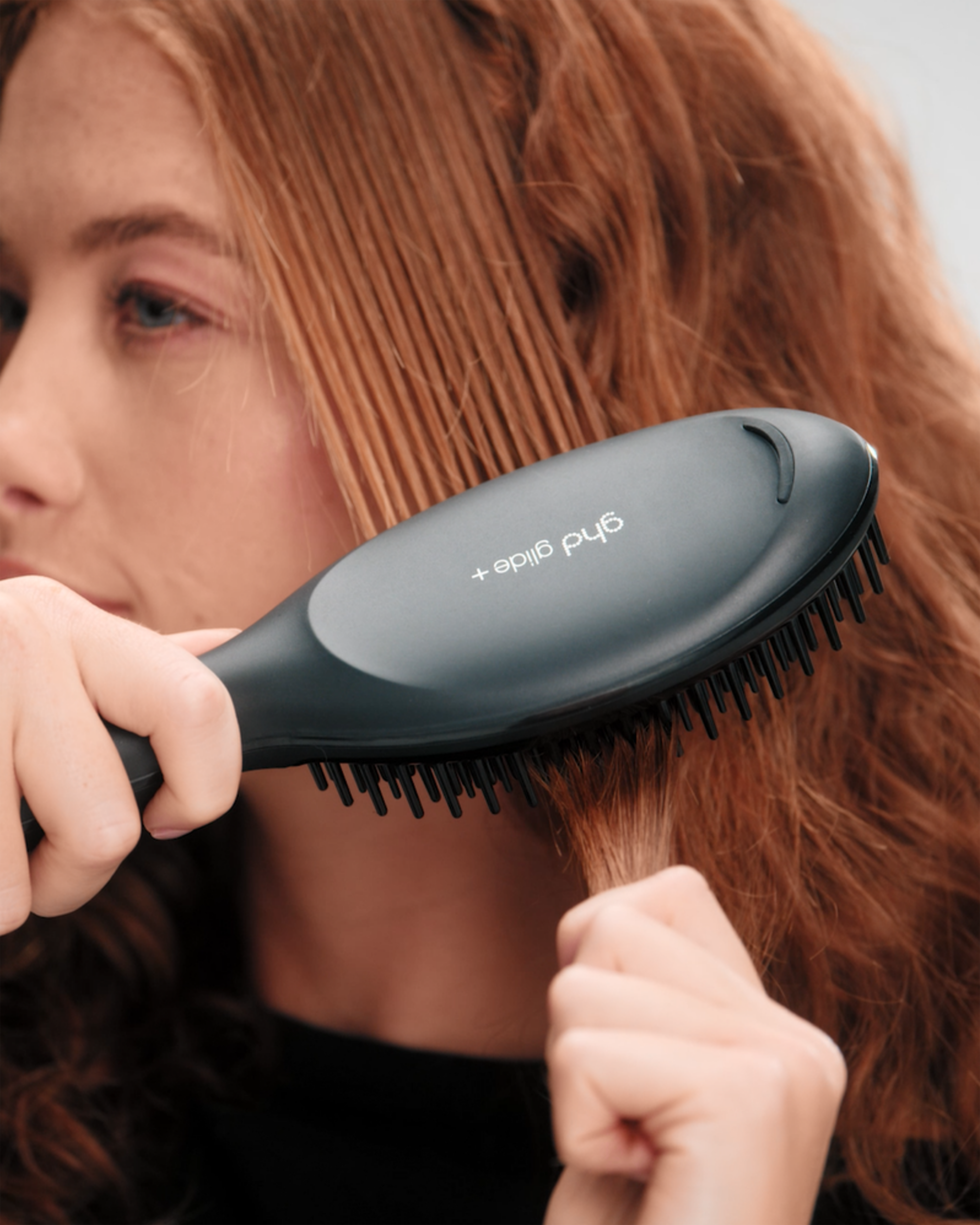 model using ghd glide+ by brushing her hair with the tool