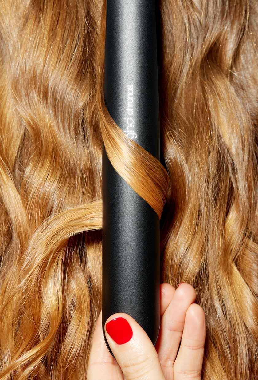 schwarzes ghd chronos Glätteisen in welligem Haar