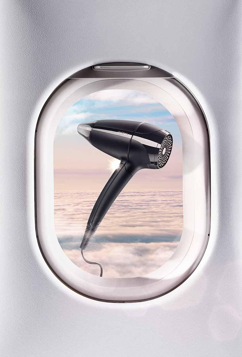 ghd flight+ schwebt vor Flugzeugfenster
