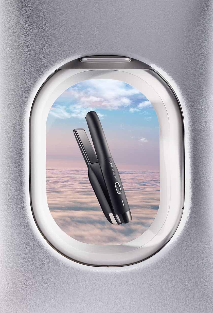 ghd unplugged Styler schwebt vor Flugzeugfenster