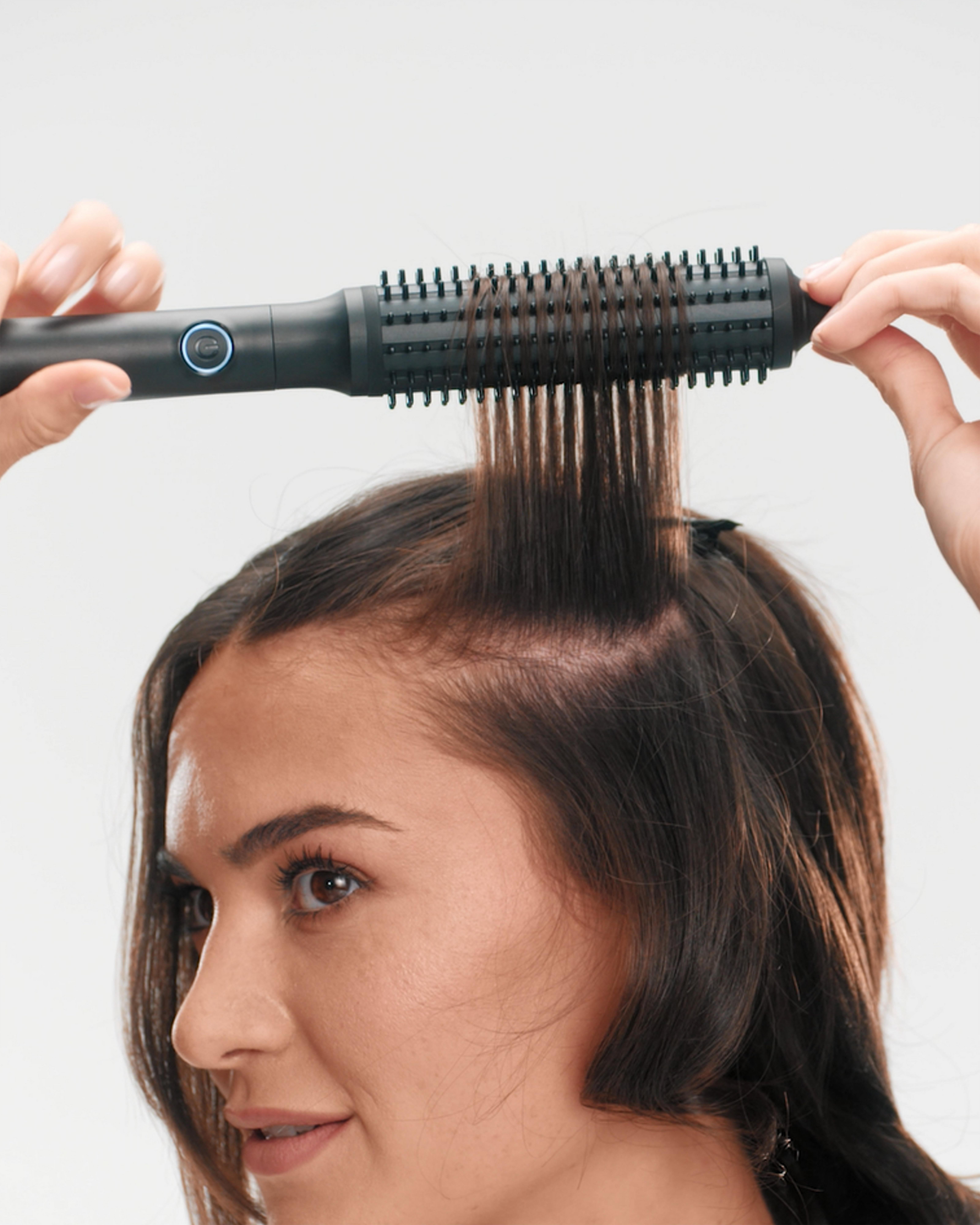 model wrapping hair around ghd rise, and gliding down toward the ends of her hair