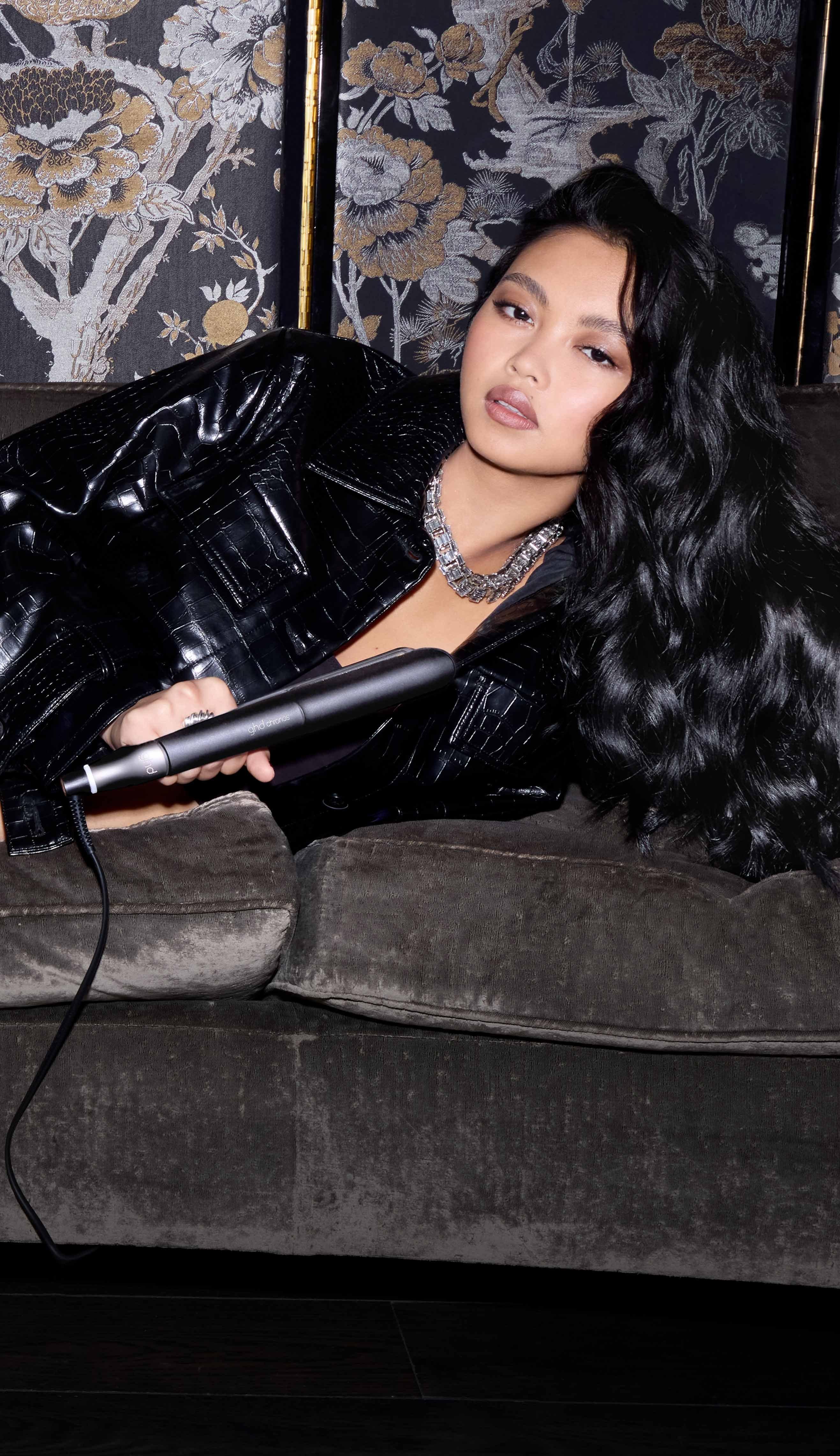 Model hält den schwarzen ghd chronos Styler